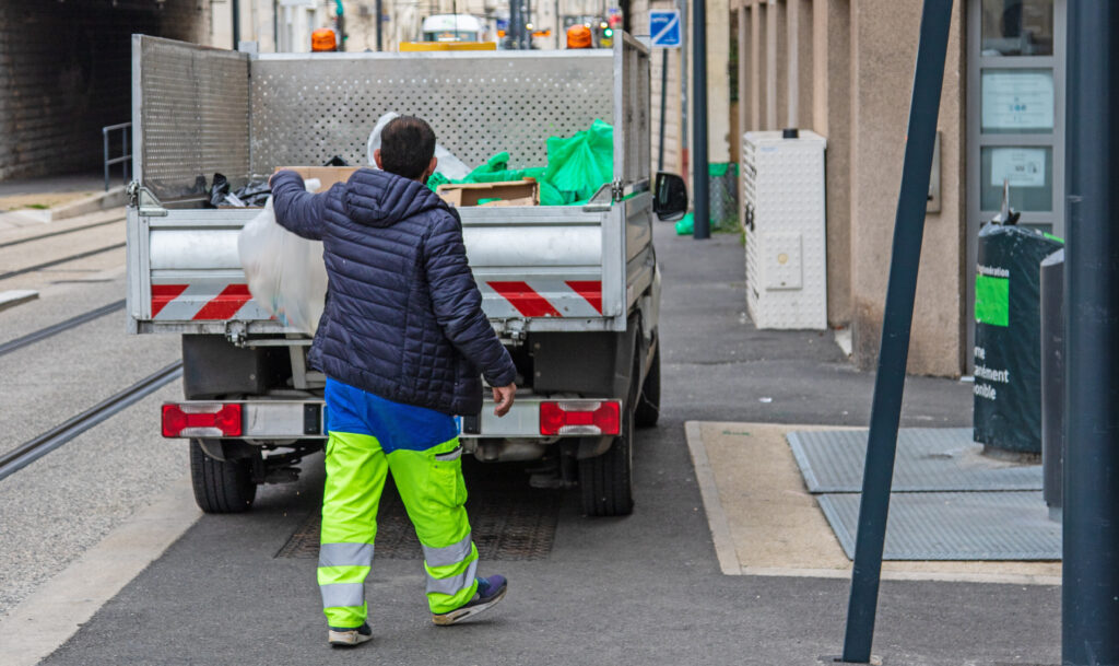 Agent de collecte des déchets chargeant des encombrants dans un camion benne en centre-ville