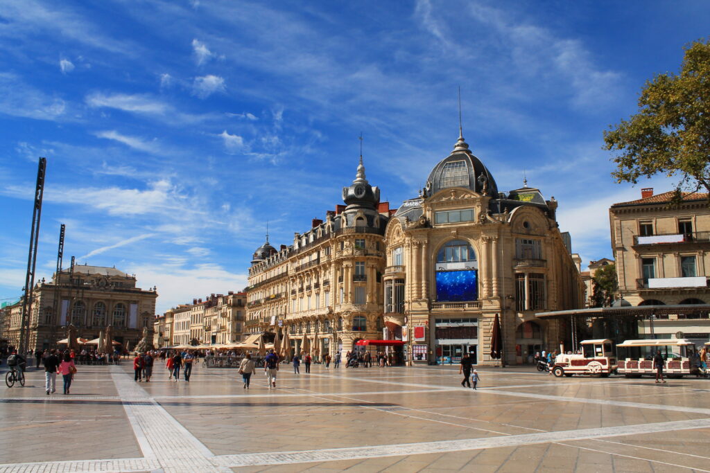 Place de la Comédie à Montpellier avec le bâtiment des Galeries Lafayette et le petit train touristique Place de la Comédie à Montpellier avec le bâtiment des Galeries Lafayette et le petit train touristique